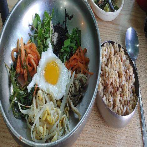 비빔밥사진입니다. 계란후라이와 채소가 그릇에 담겨있고 보리밥이 한공기 있습니다.