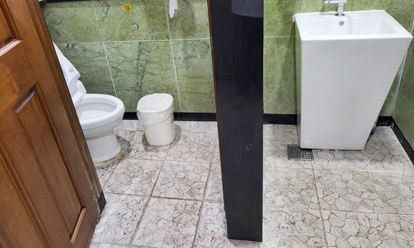 화장실 내부에 대변기 출입문과 대변기, 세면대가 보이는 사진입니다.